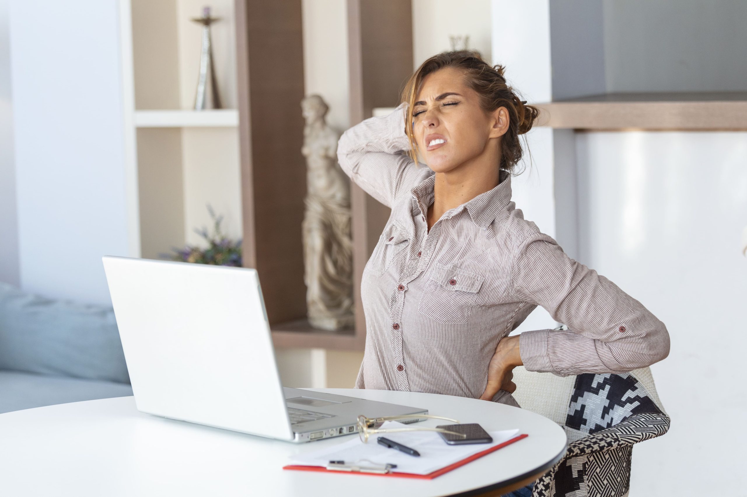 portrait-young-stressed-woman-sitting-home-office-desk-front-laptop-touching-aching-back-with-pained-expression-suffering-from-backache-after-working-laptop (2)